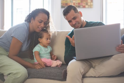 A cheerful family of three enjoying quality time together on their living room sofa, engaging with a laptop.